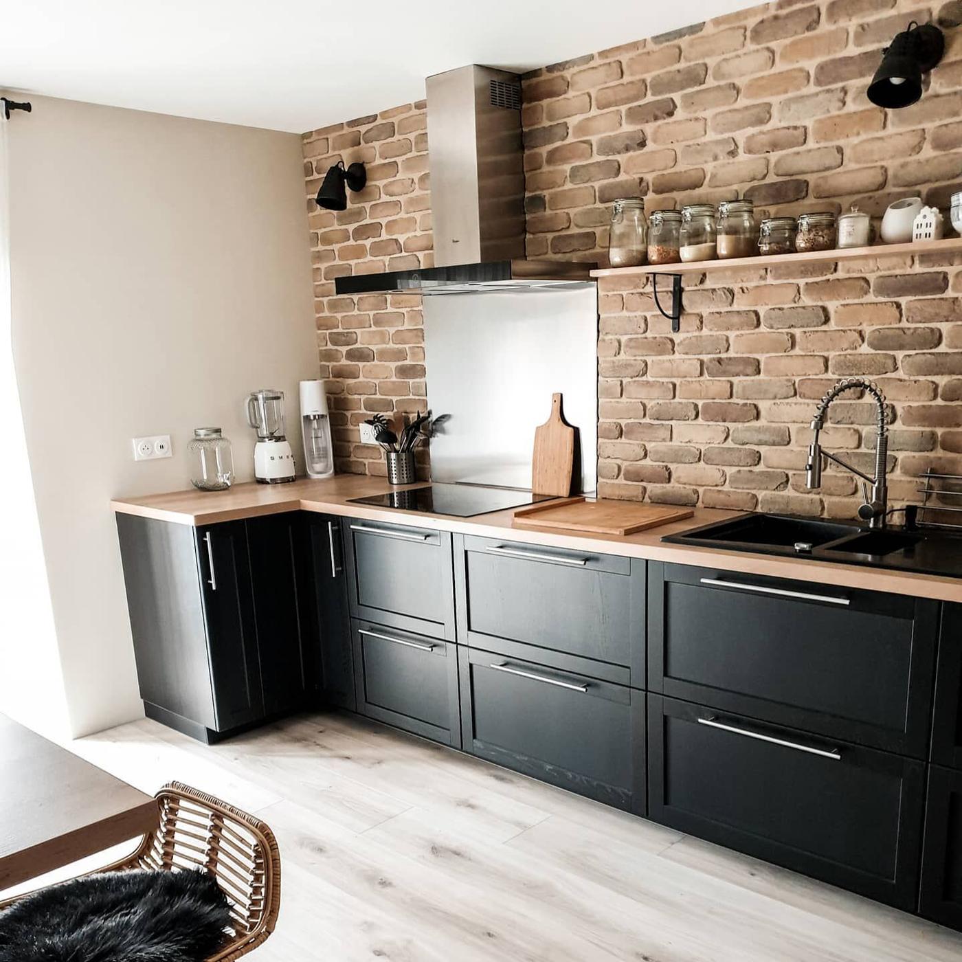 Een zwarte landelijke keuken met houten werkblad