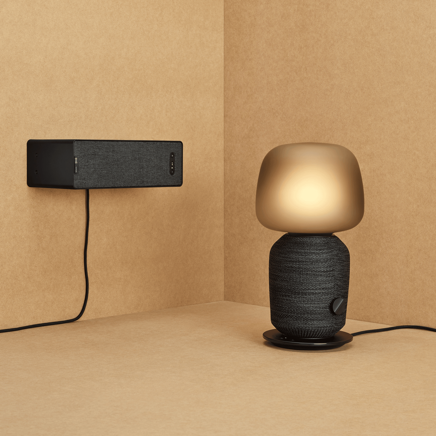 Een zwarte SYMFONISK tafellamp en een zwarte boekenkast speaker