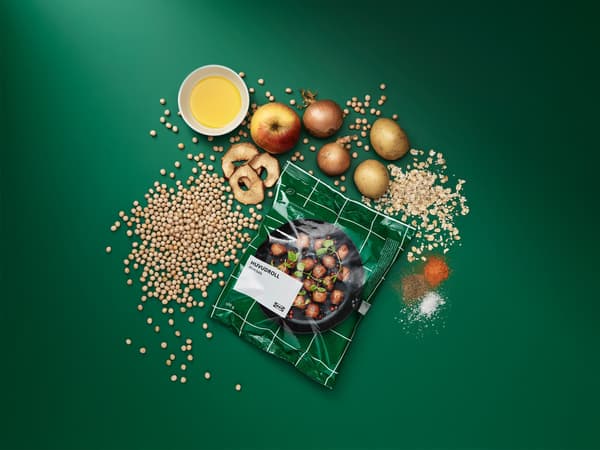 Egy csomag fagyasztott HUVUDROLL húsmentes golyó, körülötte a feldolgozatlan összetevők: zöldborsó, zab, burgonya, hagyma, alma és fűszerek.