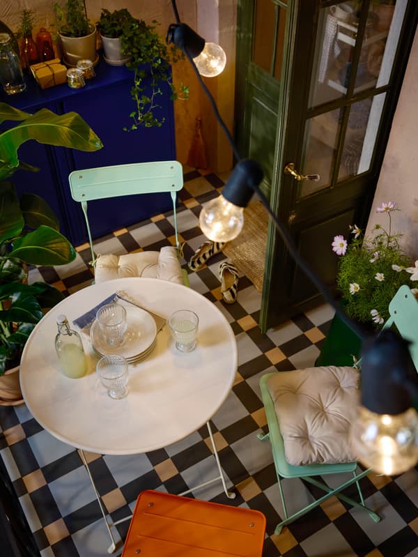 Egy erkélyen álló összecsukható SUNDSÖ asztal és szék látható.