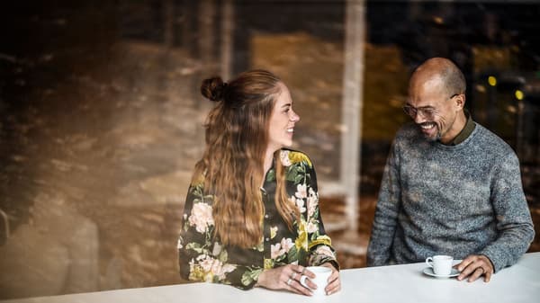 Egy férfi és egy nő beszélget egy kávézó kirakatában.