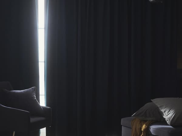 Egy hálószoba, ahol a sötétítőfüggönyök be vannak húzva, és csak egy kis fény szűrődik be.