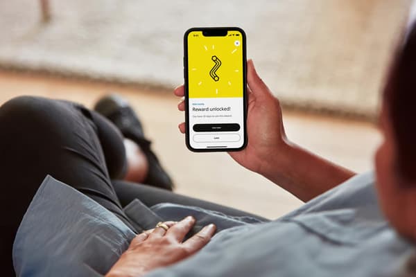 Egy kéz egy mobiltelefont tart, amelynek képernyőjén egy QR-kód látható.