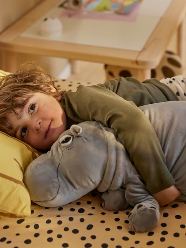 Egy kisfiú SANDLÖPARE plüss vízilovat tart a karjaiban.