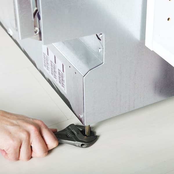 Egy mosogatógépet beszerelő személy.