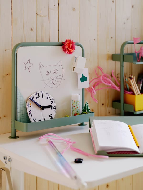 Egy ülő-/álló munkához alkalmas RELATERA asztalra szerelt RELATERA üzenőtáblát látunk.