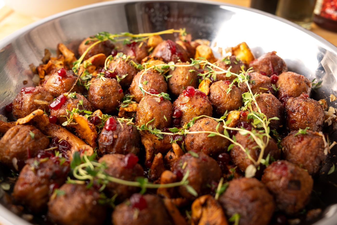 Eierschwammerln, Köttbullar & Preiselbeer-Glasur in einer Pfanne präsentiert.