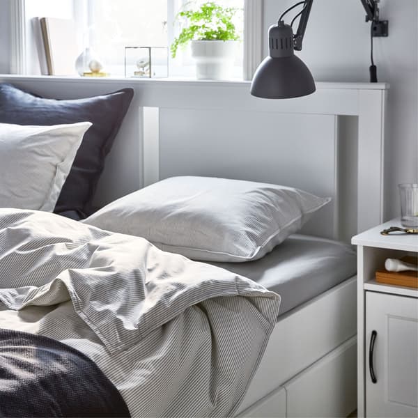 Ein Bett seitlich mit aufgeschlagener Decke.