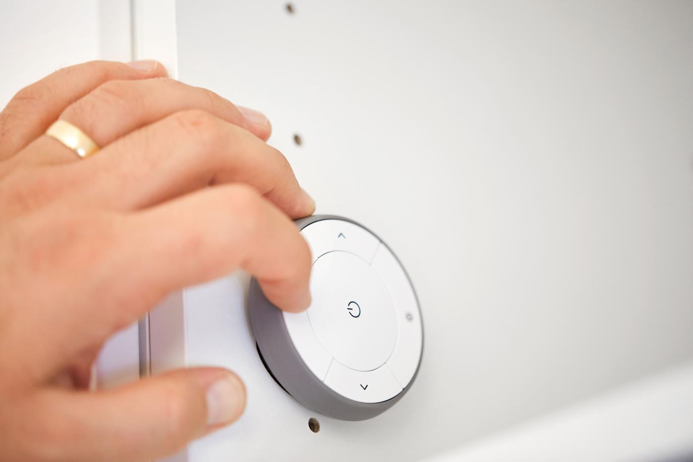 Ein Bildschirm steht auf einem weissen Schreibtisch, der höhenverstellbar ist. Daneben eine weisse, verstellbare Schreibtischlampe.