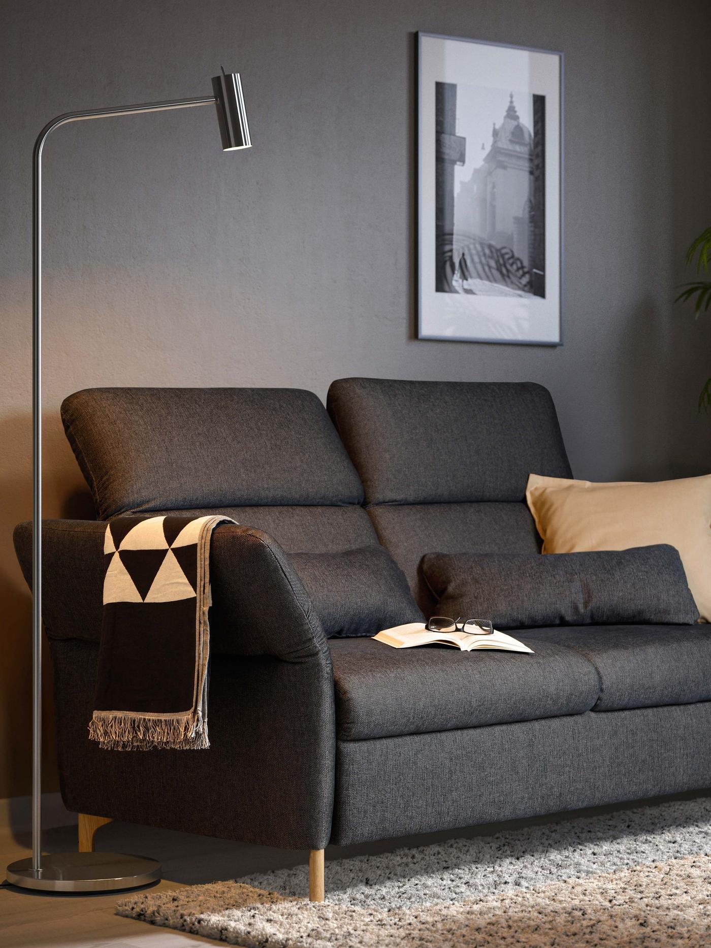 Ein dunkelgraues FAMMARP 2er Sofa mit verstellbaren Rückenlehnen und Armlehnen steht vor einer grauen Wand.