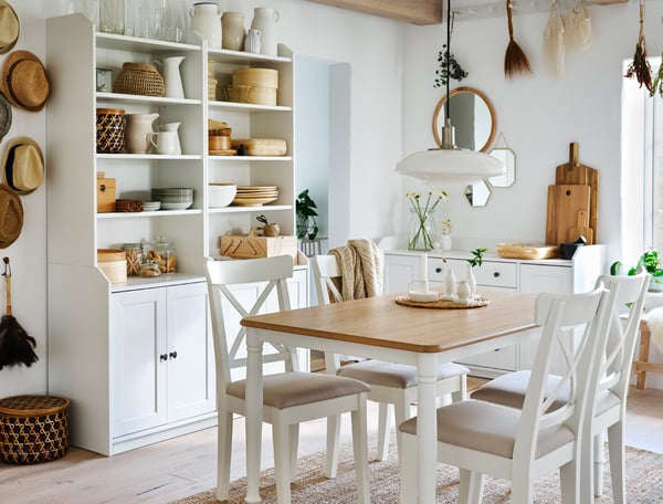 Ein Essbereich mit einem Tisch und Stühlen und offenen HAUGA Kleiderschränken mit 3 Schubladen in Weiß und einer weißen HAUGA Kommode an den Wänden