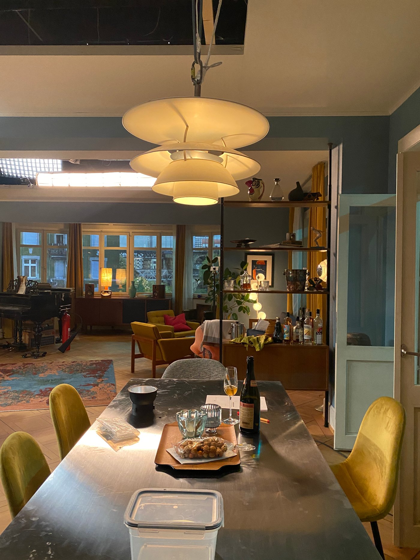 Ein Esstisch mit gepolsterten Stühlen und einer Lampe arüber steht in einem offenen Wohnraum.