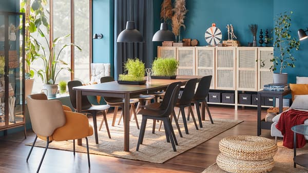 Ein Esszimmer für viele Gäste mit einem grossen dunkelbraunen Ausziehtisch, acht Stühlen in Anthrazit und einem gelben Sessel.