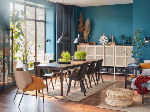 Ein Esszimmer mit einem großen dunkelbraunen Ausziehtisch, acht Stühlen in Anthrazit, einem gelbem Sessel und einem Aufbewahrungssystem mit Türen aus Bambus