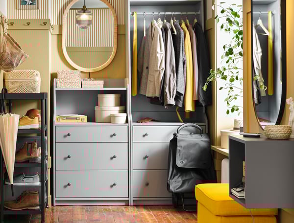 Ein Flur mit verschiedenen grauen HAUGA Elementen, u. a. ein offener Kleiderschrank mit drei Schubladen und eine Kommode, in denen Kleidung und Accessoires unterkommen