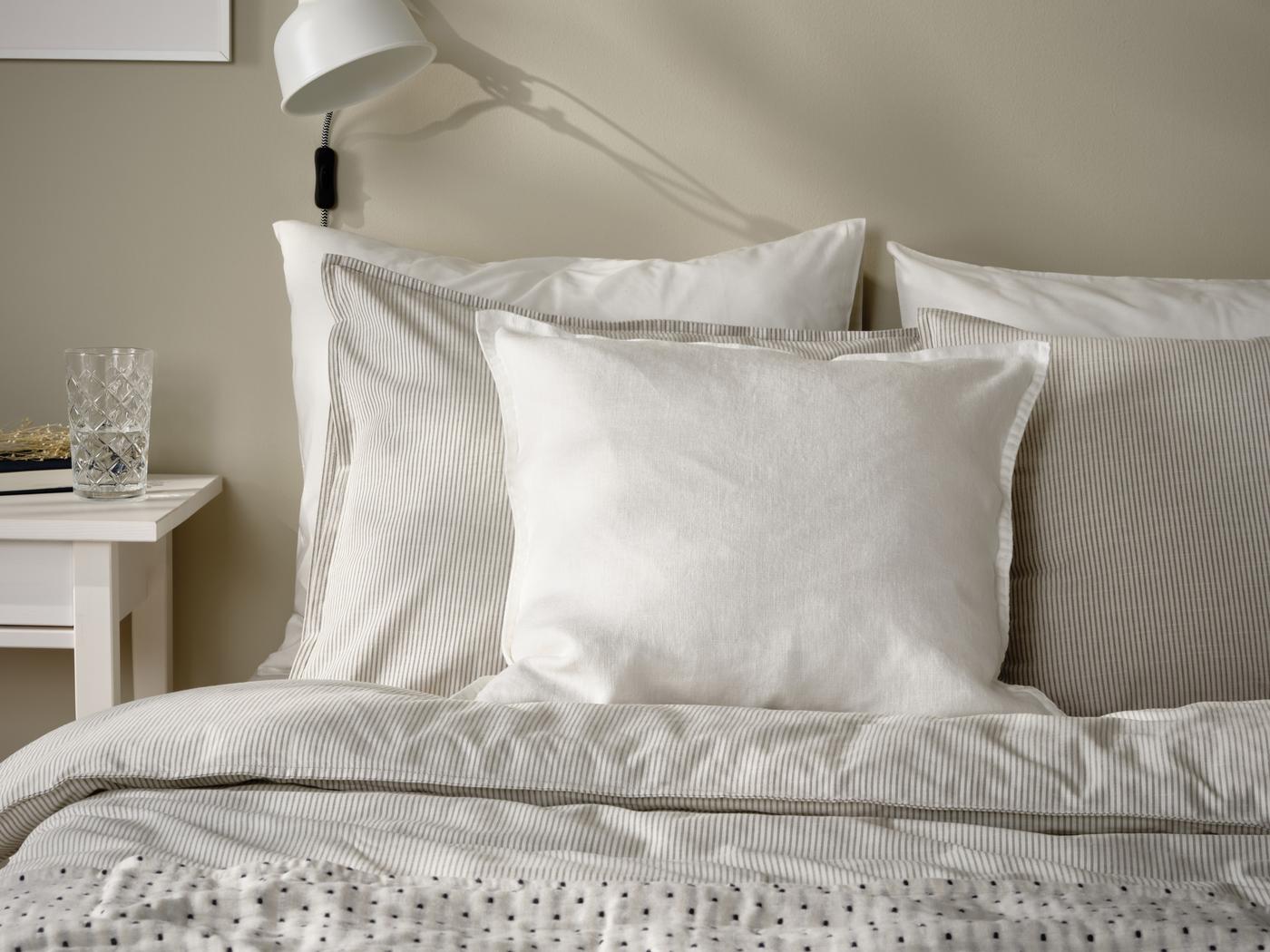 Ein gemachtes Bett mit weiß grauem Überzug