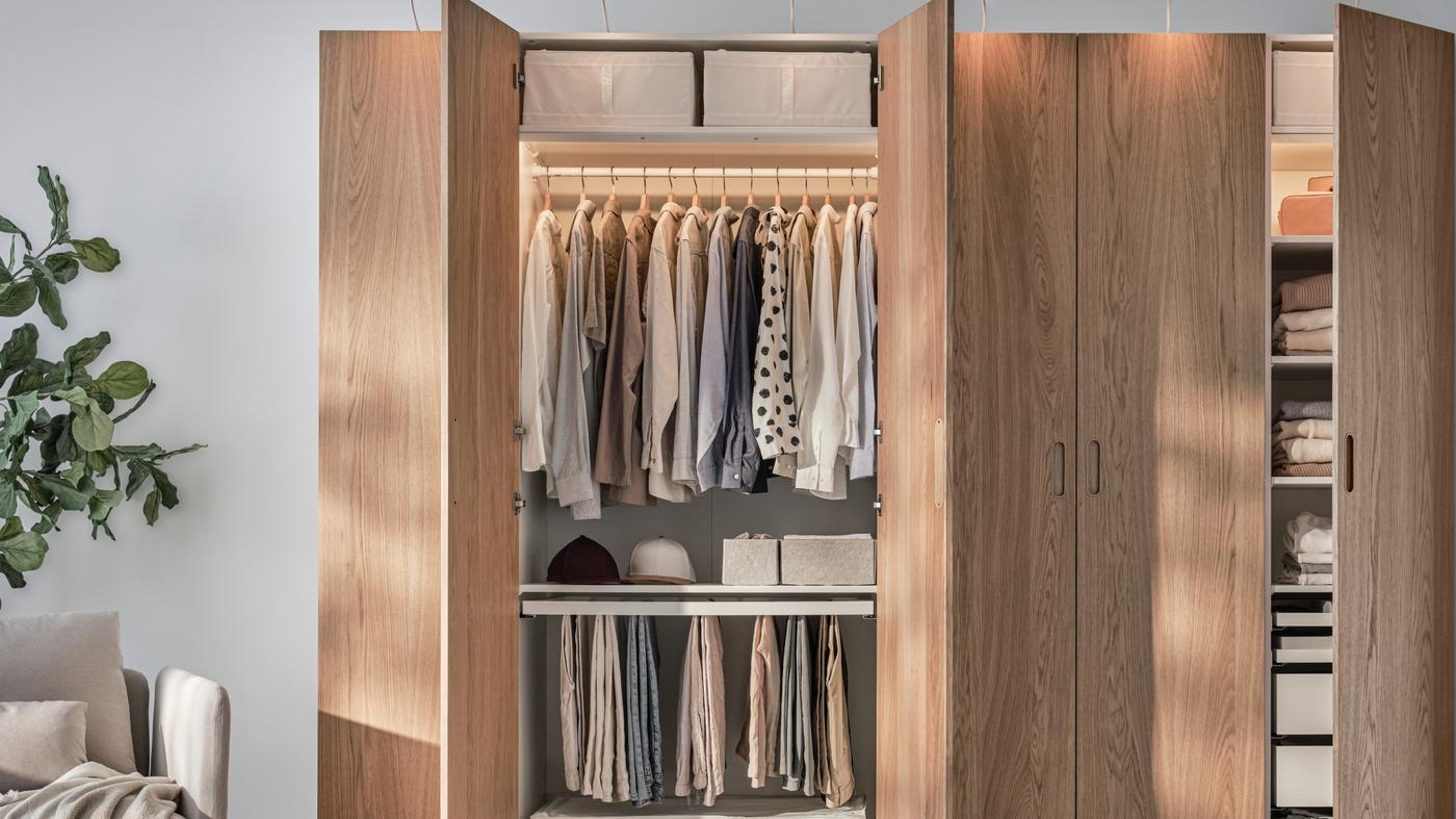 Ein geöffneter brauner PAX Schrank mit Klamotten.