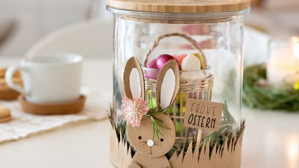 Ein Glas mit Pappe zu einem Osternest gestaltet.