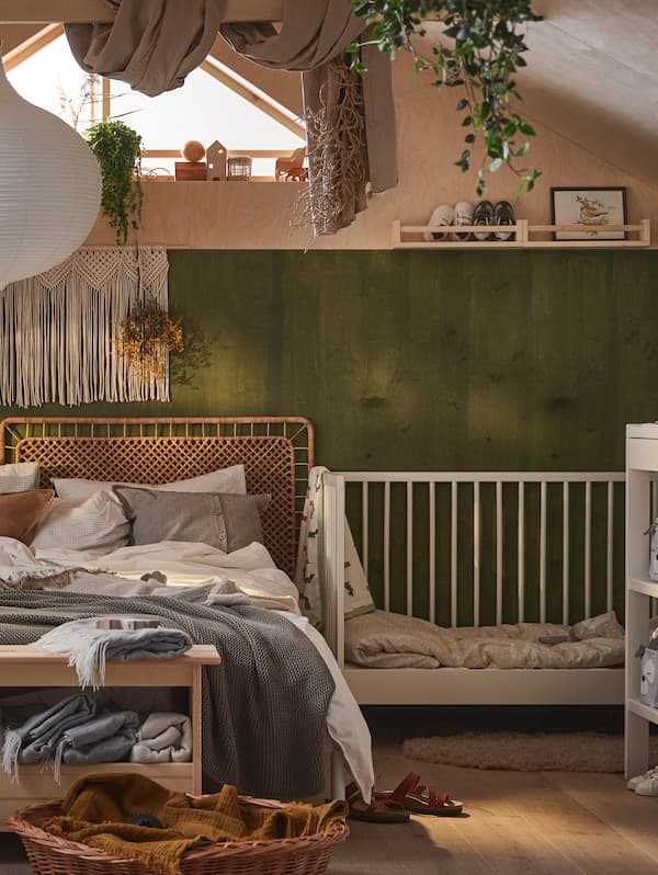 Ein GULLIVER Babybett in einem Raum im Boho-Stil. Das Doppelbett daneben ist mit verschiedenen neutralfarbenen Textilien dekoriert.