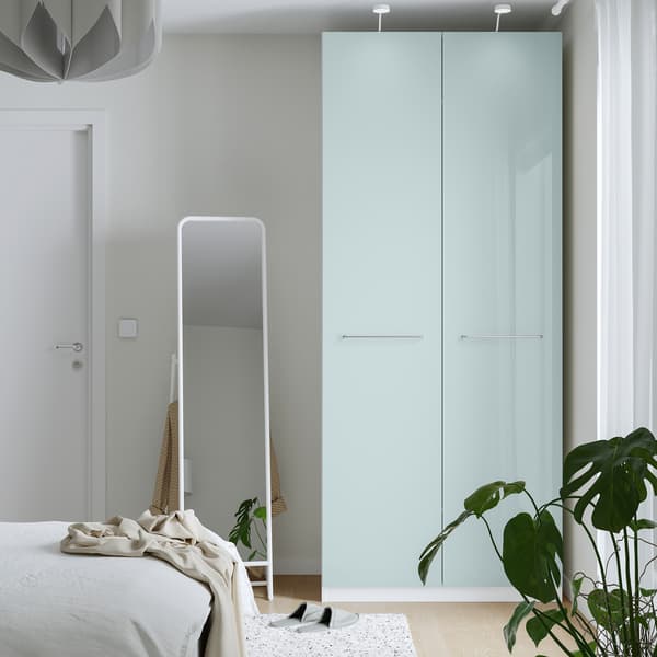 Ein hellblauer PAX-Kleiderschrank in einem Schlafzimmer mit einem Standspiegel auf der linken Seite