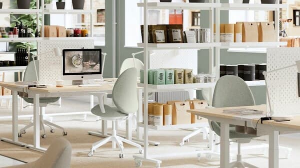 Ein helles freundliches Büro mit Schreibtischen in Birke und Weiß mit Grün Weißen Drehstühlen. 