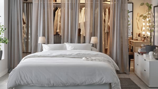 Ein helles Schlafzimmer mit einem großen Bett und einer offenen Kleideraufbewahrungslösung.