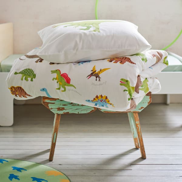 Ein Hocker, auf dem eine JÄTTELIK Bettwäsche mit Dinosauriermuster liegt