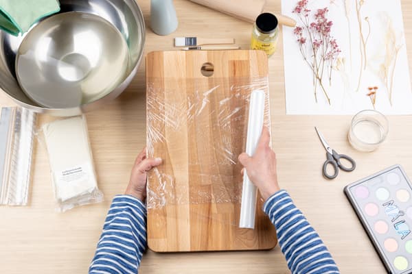 Ein Holzbrett wird mit Folie umwickelt