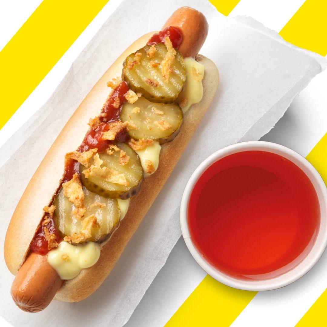 Ein Hot Dog und ein Schwedenkracherl vor einem gelb-weiß gestreiftem Hintergrund.