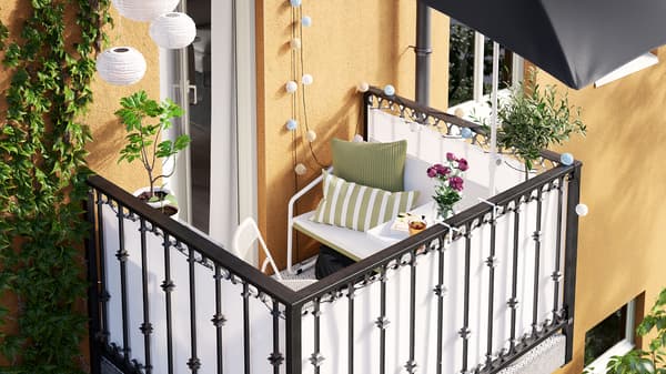 Ein hübsch gestalteter Mini-Balkon in einem gelben Mehrfamilienhaus.