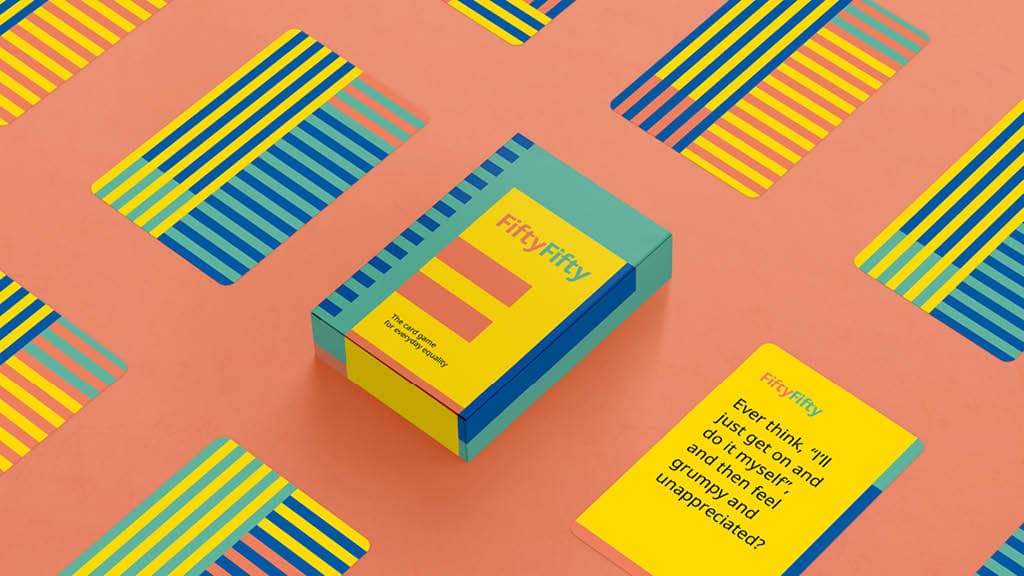 Ein Ikea Brettspiel "FittyFitty" in einer Bunten Box umgeben vo ebenso bunnten prints auf einem Rosa Hintergund