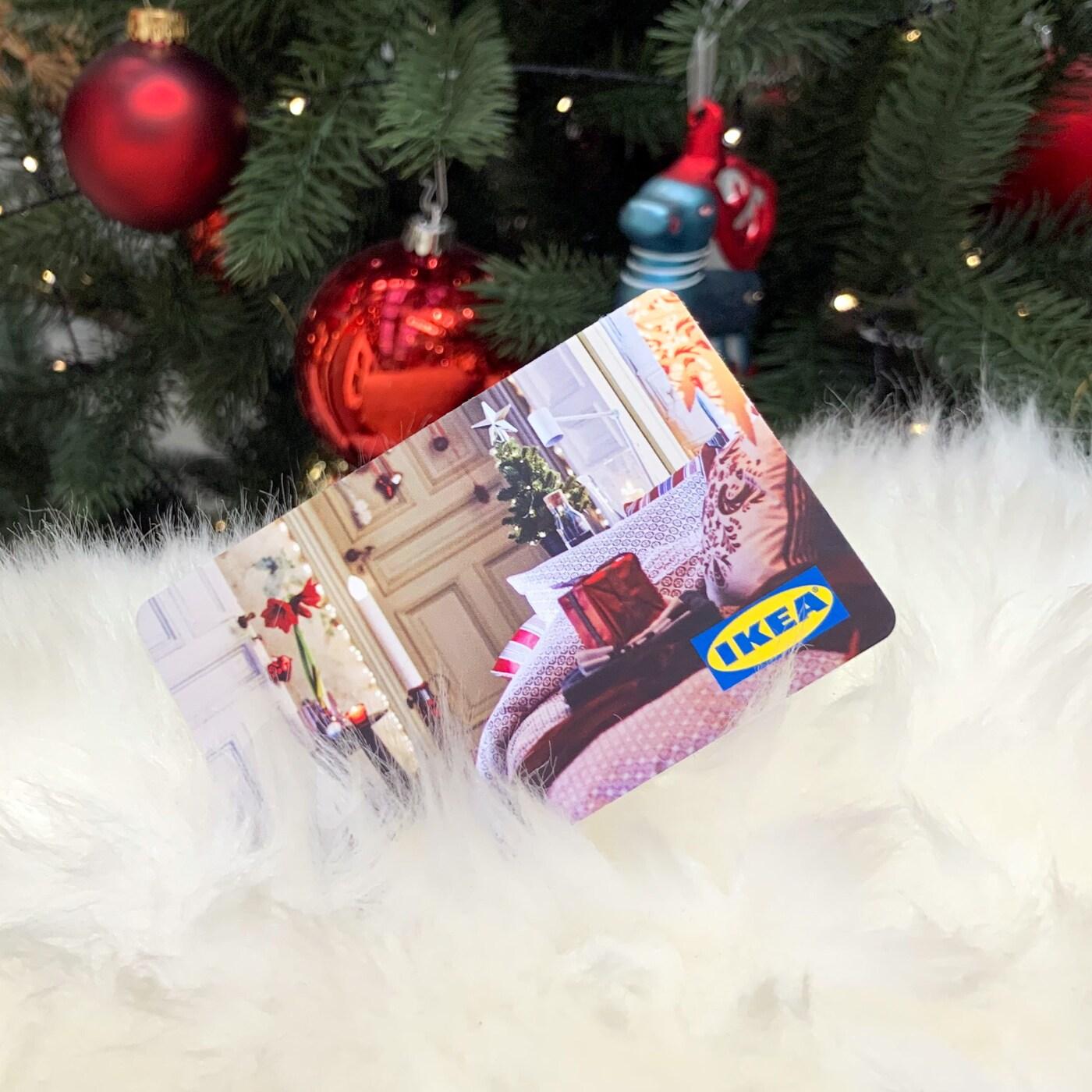 ein IKEA Gutschein auf einer Wolldecke und dahinter ein Weihnachtsbaum