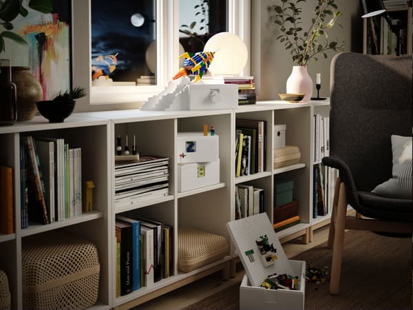Ein IKEA KALLAX Regal mit Büchern und Deko und obendrauf eine Rakete gebaut aus LEGO.