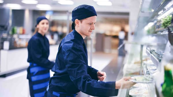 Ein IKEA Lehrling zur Systemgastronomiefachkraft steht im Küchenbereich und hat Spaß an der Arbeit
