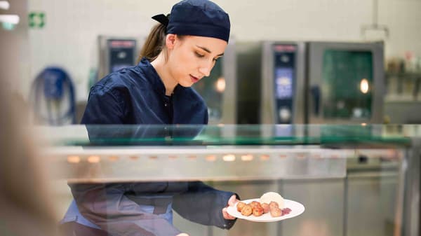 Ein IKEA Lehrling zur Systemgastronomiefachkraft steht im Küchenbereich und lächelt