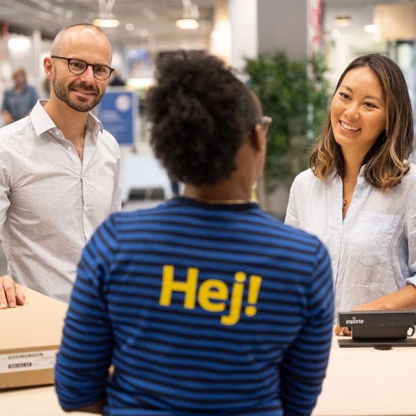 Ein IKEA-Mitarbeiter begrüsst zwei Kunden im Geschäft.