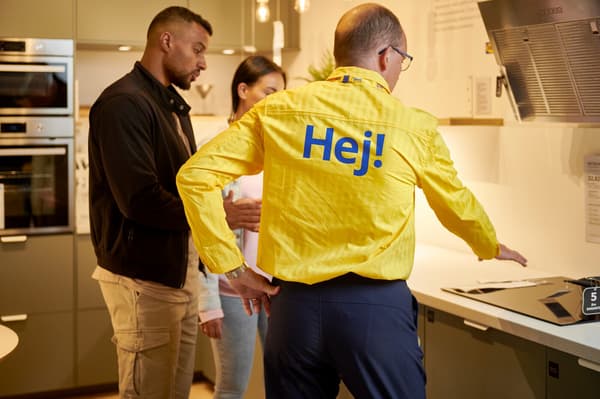 Ein IKEA Mitarbeiter bereit zwei Personen in der Küchenabteilung.