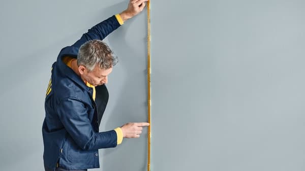 Ein IKEA Mitarbeiter nimmt Maße an einer Wand.