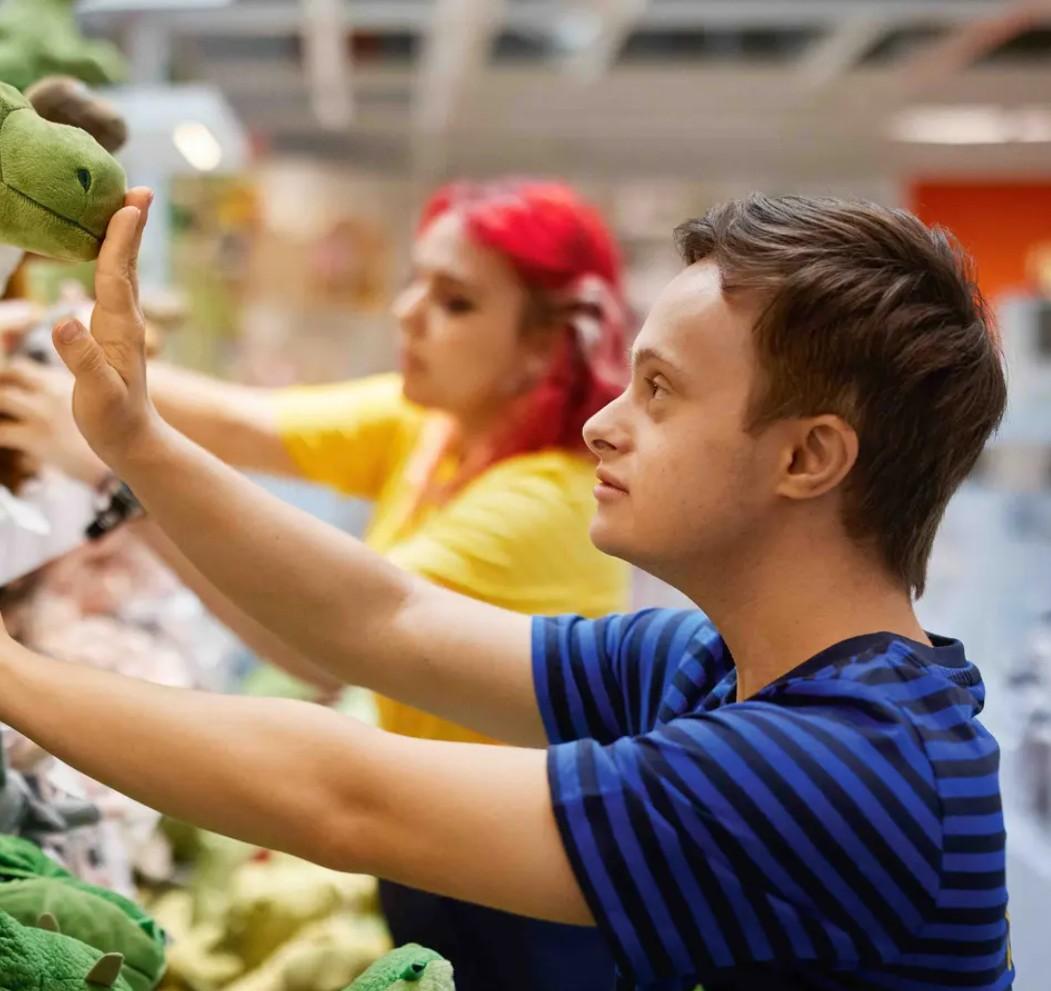 Ein IKEA Mitarbeiter räumt ein Regal ein.