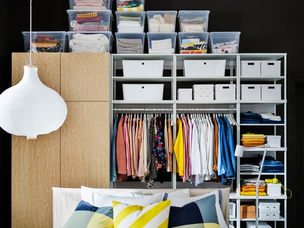 Ein IKEA PLATSA Regal mit SAMLA Boxen und Kleidungsstücken.