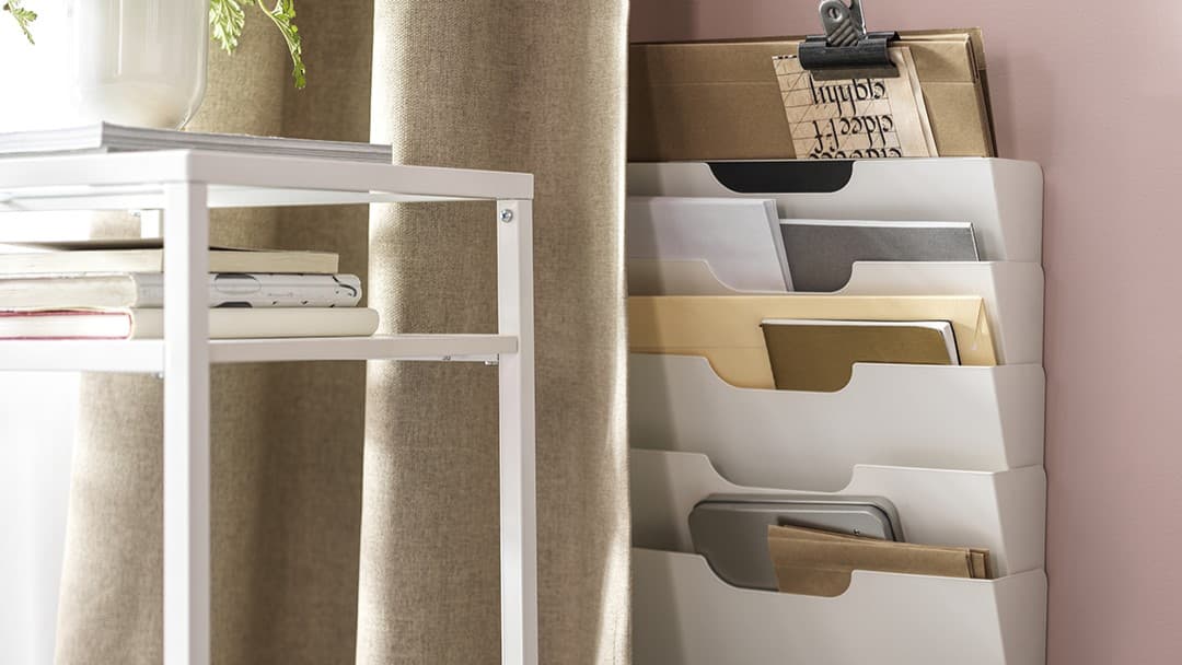 Ein IKEA Zeitrschriftenhalter an einer rosafarbenen Wand.