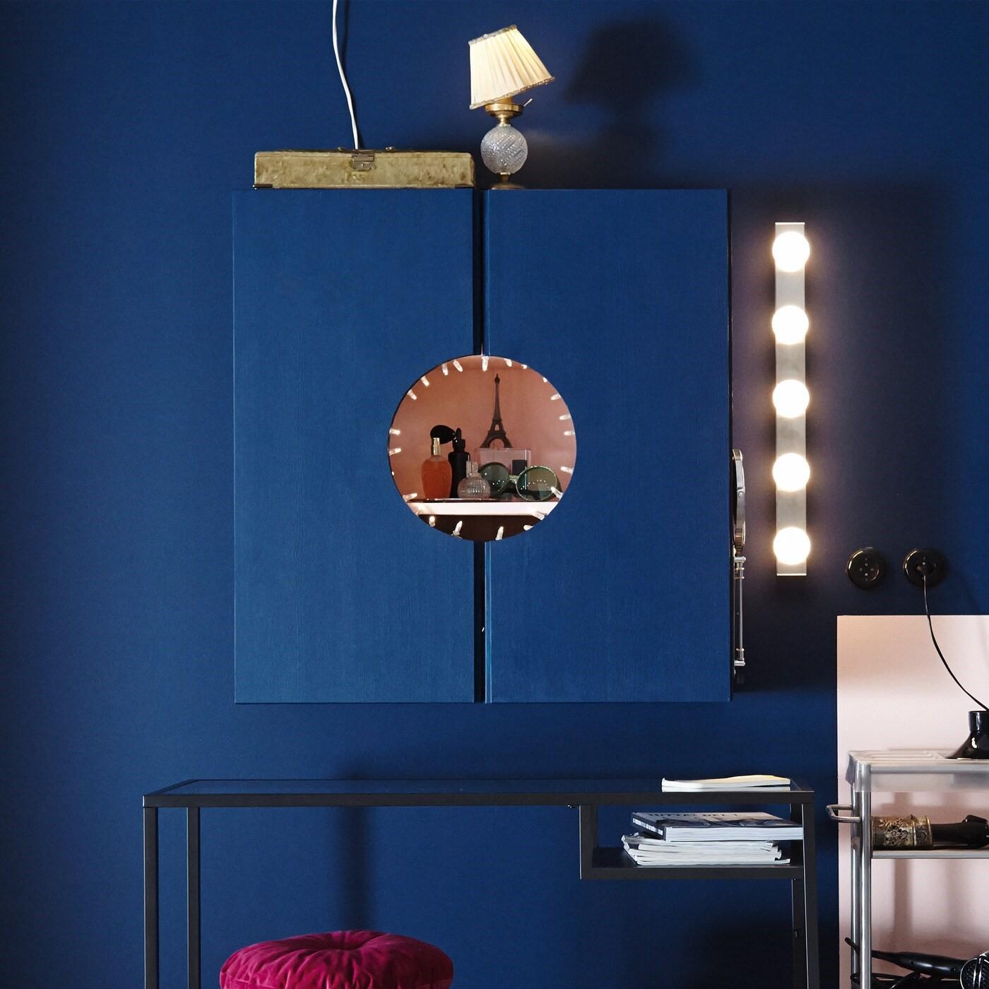 Ein IVAR Schrank, der innen rosafarben und außen blau gestrichen wurde. In der Mitte der Türhälften wurde ein Kreis ausgesägt, der den Schminktisch verbirgt und zugleich präsentiert.