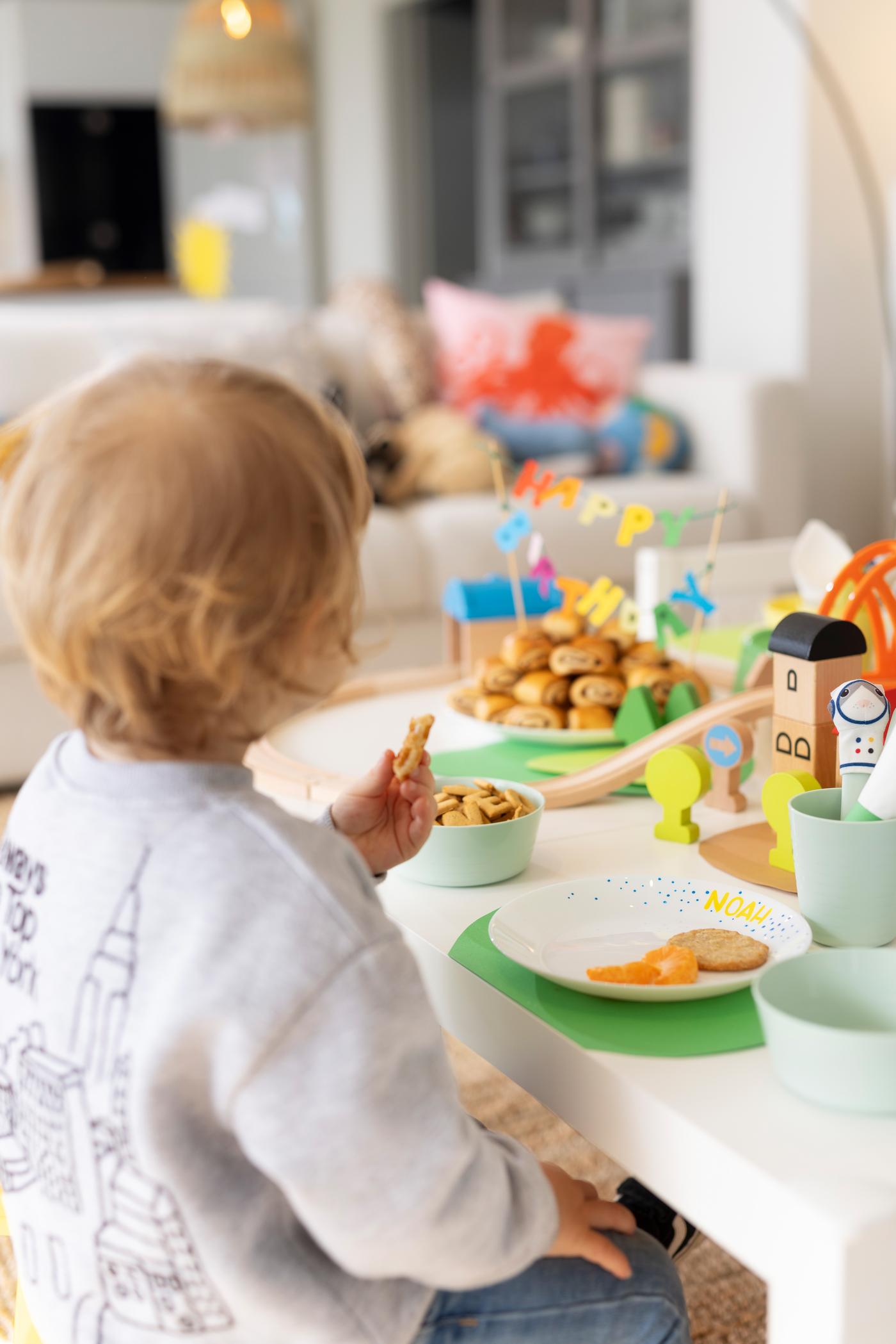 Ein Junge sitzt am Geburtstagstisch und isst. 