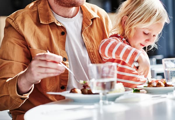 Ein Kind isst gemeinsam mit einem Erwachsenen Köttbullar in einem IKEA-Restaurant.
