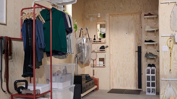 Ein kleines Vorzimmer mit hohen Wänden, Kleiderstangen und Konsolen, die senkrecht montiert wurden, um Platz für Schuhe und Kleidung zu machen.