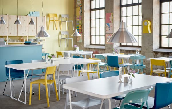 Ein kreatives & farbenfrohes Café mit weißen BACKARYD Tischen & Stühlen in Gelb, Türkis, Weiß & Blau