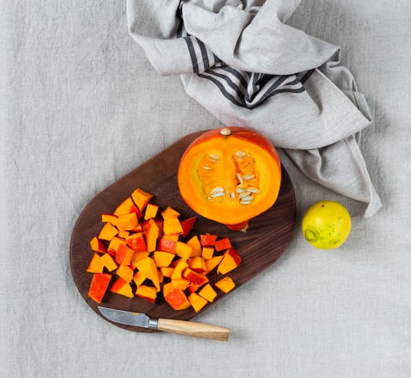 Ein Kürbis wird für selbstgemachten Kürbis-Karotten-Aufstrich vorbereitet und geschnitten.