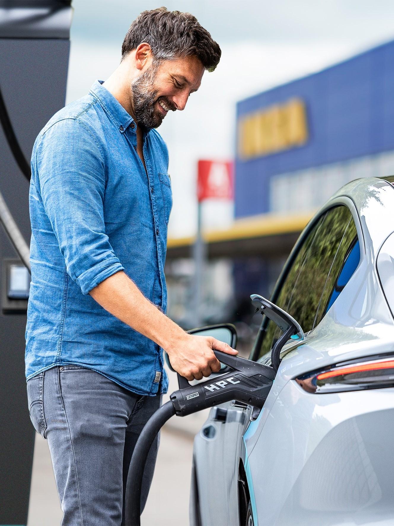 Ein Kunde lädt sein Elektroauto an einer Mer Ladestation auf einem IKEA Parkplatz.