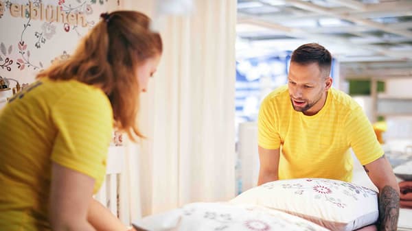 Ein lächelnder IKEA Lehrling zum Einzelhandelskaufmann steht im Einrichtungshaus