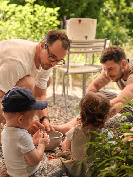 Ein männliches Pärchen spielt mit den Kindern im Garten. 